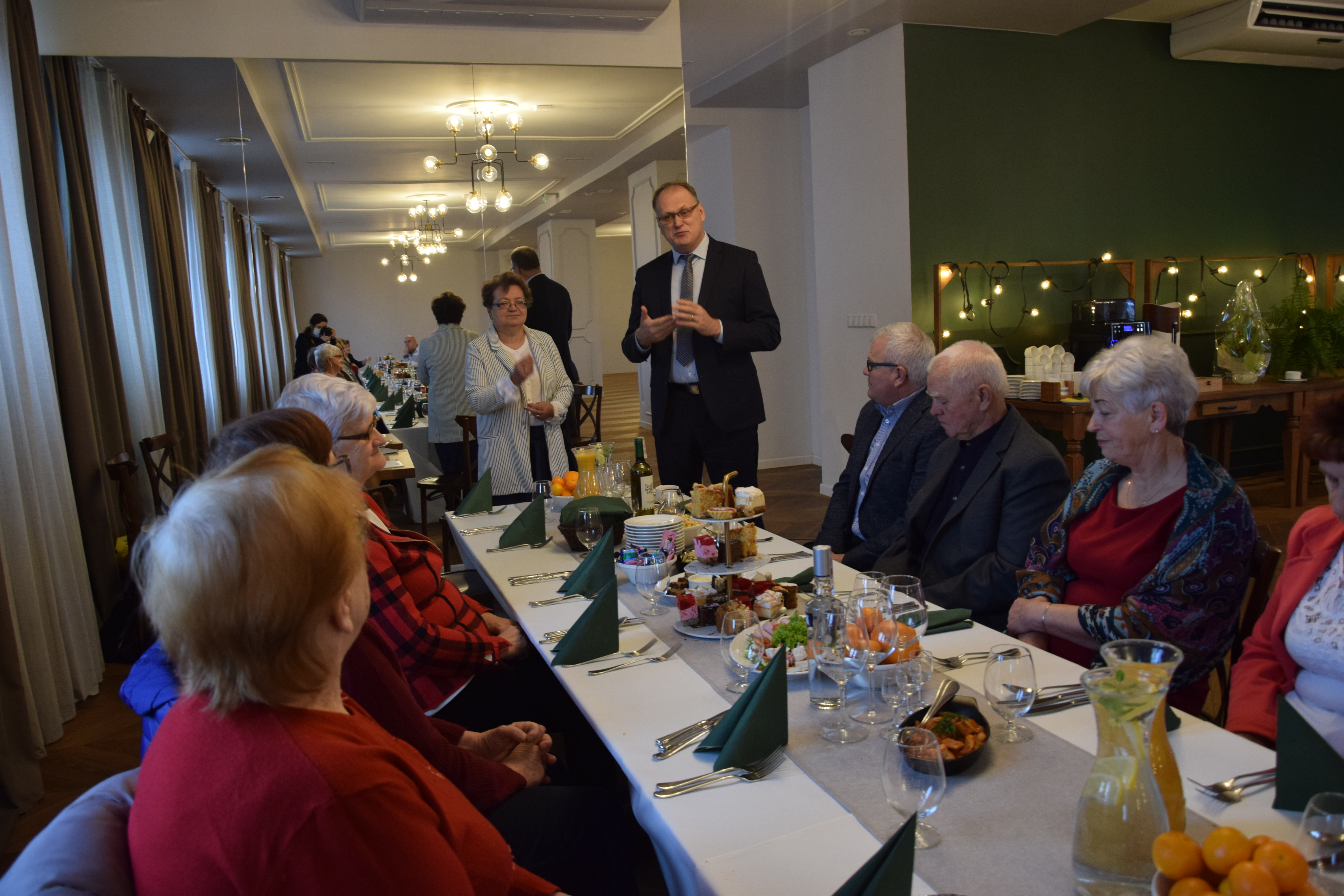 Prezydent Miasta Jarosław Ferenc wraz z radnym Grzegorzem Mineckim prowadzi rozmowę przy stole w restauracji z członkami Polskiego Związku Niewidomych.